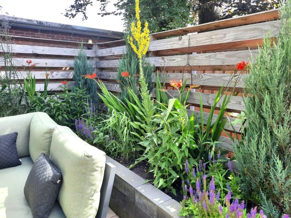 tuin elly kleurrijke beplanting achter bank bw